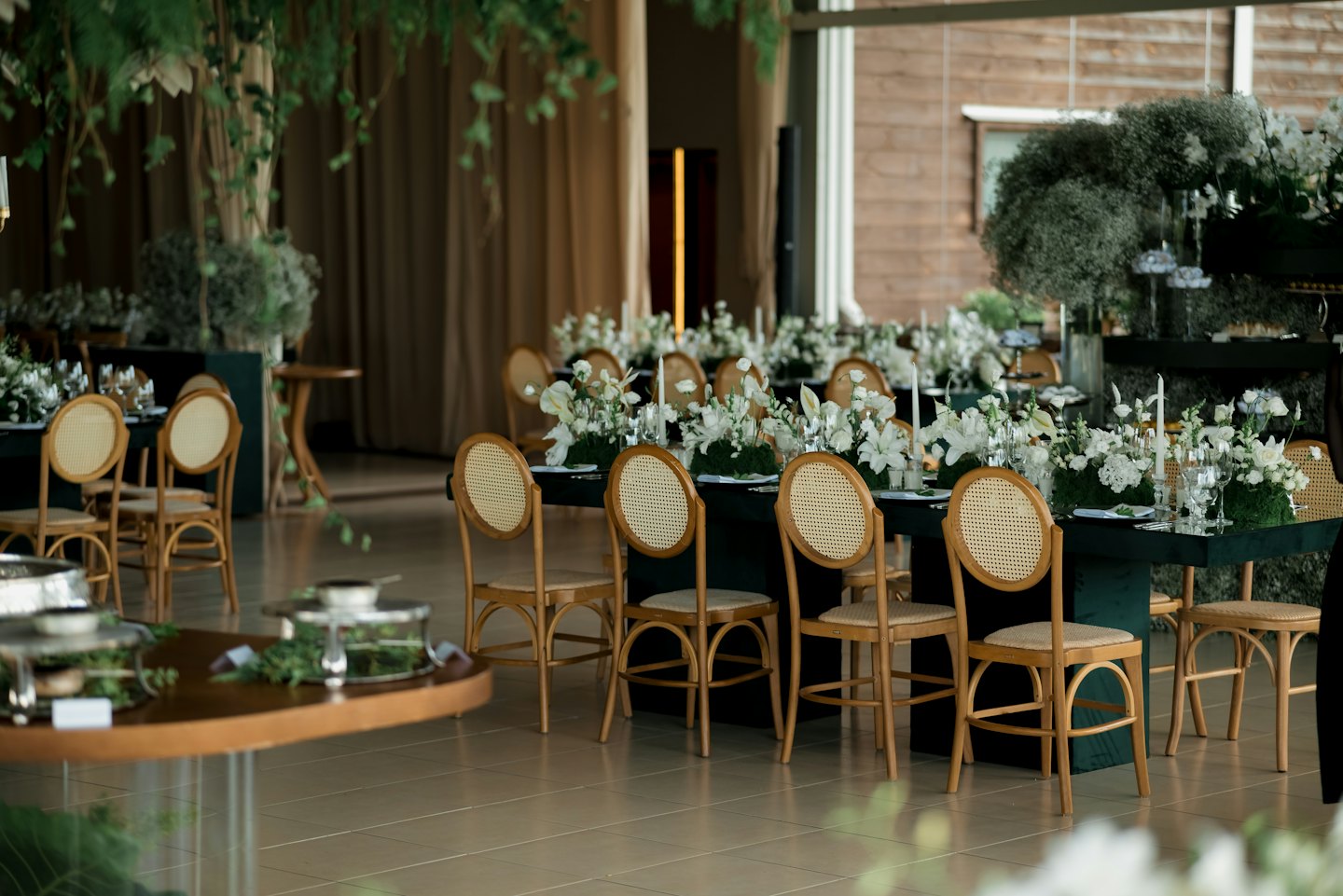 Spazio eventi elegante con lunghi tavoli, composizioni floreali e candele.